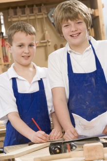 Two students smiling over a hands-on woodworking and building project