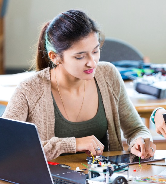 An older student focused on wiring her engineering project